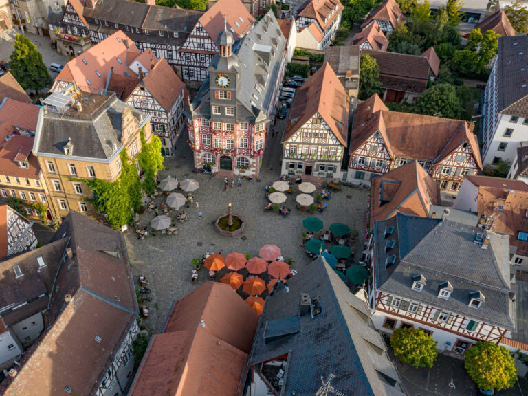Drohnenaufnahme vom historischen Marktplatz in Heppenheim mit Fachwerkhäusern und Sonnenschirmen