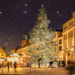romantische Abendstimmung mit vielen Adventslichtern und funkelndem Sternenhimmel. Im Vordergrund ein großer festlich geschmückter Weihnachtsbaum auf dem Marktplatz in Darmstadt