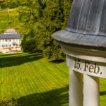 Foto im Stadtpark Fürstenlager. Blick vom Freundschaftstempel aus die Wiese hinunter zum Herrenhaus. Sonniges Wetter, leuchtend grüne Vegetation